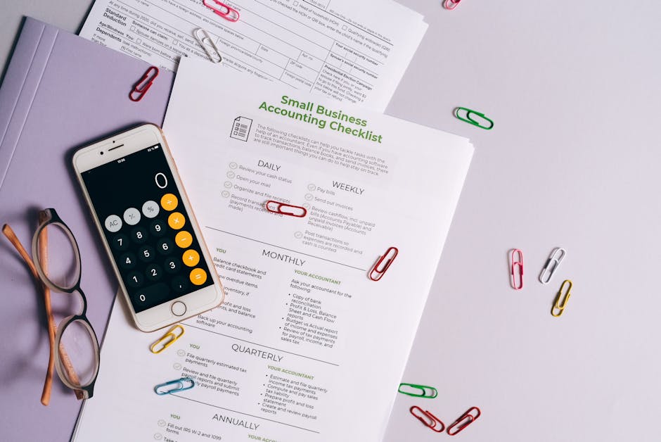 Top view of accounting essentials including smartphone, eyeglasses, and paperwork.